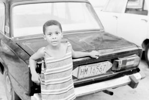 A Young Cuban Boy Strikes a Pose on a Russian Car, Havana, Cuba
